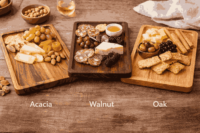 Acacia, walnut, and oak wooden serving trays side by side with cheese, crackers, olives, and charcuterie for wood comparison
