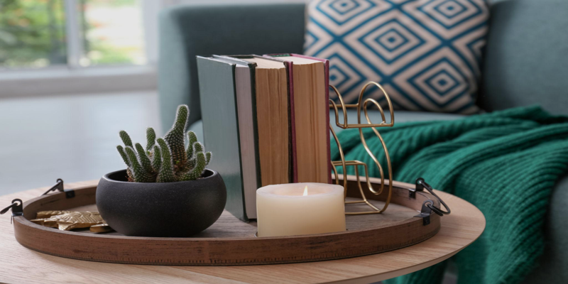 Wooden coffee table tray with books, candle, and small plant styled in a cozy living room to create a modern and aesthetic decor setup